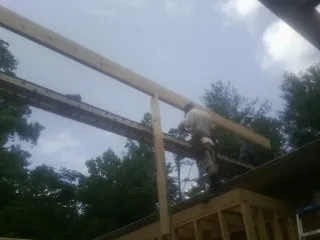 Carpenter setting a ridge beam over a new addition frame in Staatsburg