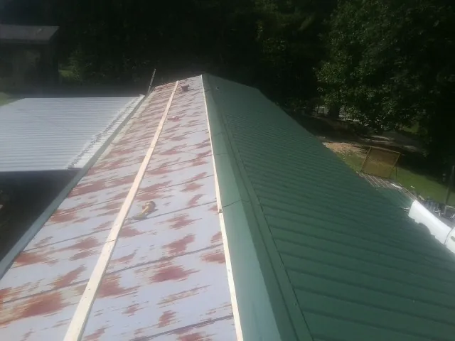 Old rusted panels beside newly installed green metal roofing — Wind Damage Roof Repair by Roofing Brothers in Staatsburg