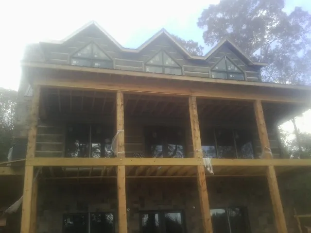Dormers and porch framing on a large log home under construction — Roof Coating work by our crew in Staatsburg
