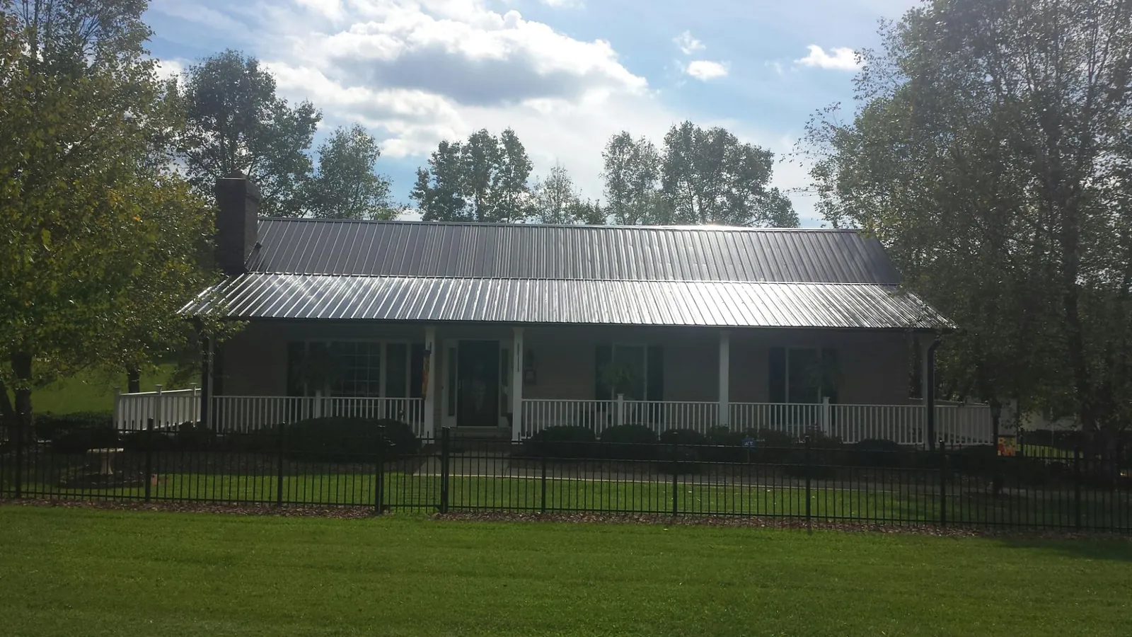 Gray metal roof on a brick ranch with a full width front porch — Gutter Guard Installation work by our crew in Staatsburg