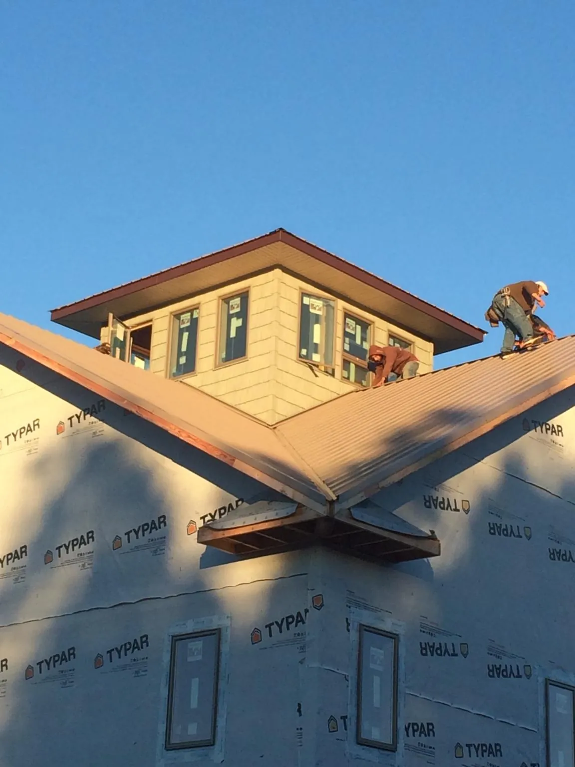 Roofers working around a rooftop cupola on a new metal roof at sunset — Roof Waterproofing in Staatsburg by Roofing Brothers